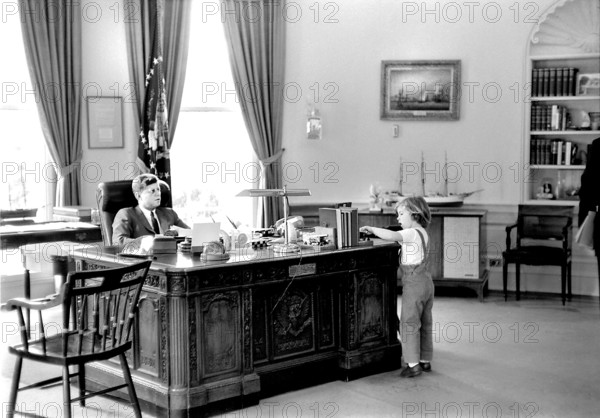 U.S. President John F. Kennedy sitting at his desk while his daughter, Caroline Kennedy, visits the Oval Office, White House, Washington, D.C., USA, Robert Knudsen, White House Photographs, May 16, 1962