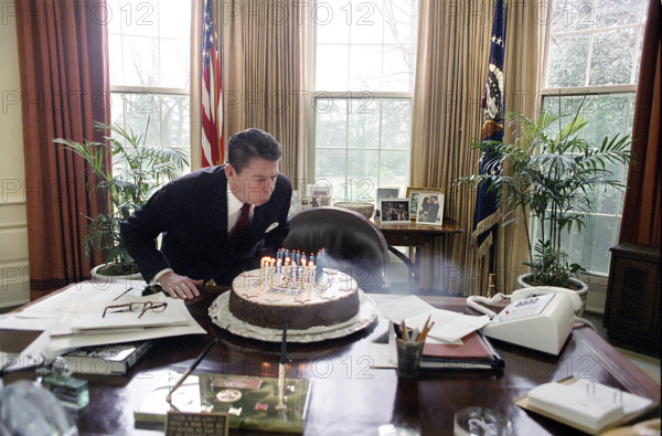 U.S. President Ronald Reagan blowing out candles on a cake while celebrating his birthday in Oval Office of the White House, Washington, D.C., USA, President Ronald Reagan White House Photographic Office, February 6, 1982