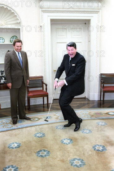 U.S. President Ronald Reagan putting a golf ball with American professional golfer Raymond Floyd looking on in the Oval Office of the White House, Washington, D.C., USA, President Ronald Reagan White House Photographic Office, June 24, 1986