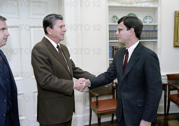 U.S. President Ronald Reagan greeting John Roberts during a photo opportunity with members of the White House Counsel's Office in the Oval Office of the White House, Washington, D.C., USA, President Ronald Reagan White House Photographic Office, January 6, 1983