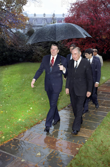 U.S. President Ronald Reagan holding umbrella while walking with President Chaim Herzog of Israel outside of White House Oval Office, Washington, D.C., USA, President Ronald Reagan White House Photographic Office, November 10, 1987