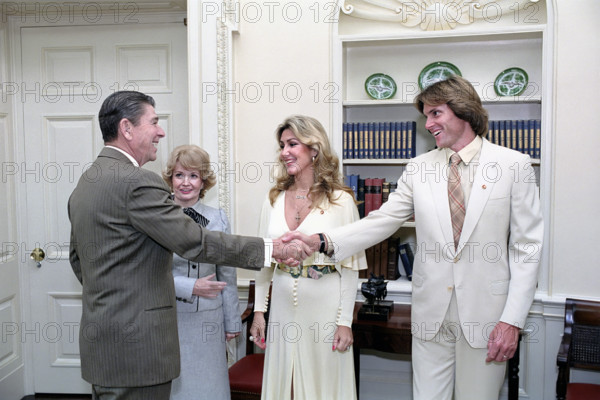 U.S. President Ronald Reagan shaking hands with Bruce Jenner, with his wife Linda Jenner and Margaret Heckler at signing ceremony for proclamation for "National Diabetes Month" in White House Oval Office, Washington, D.C., USA, President Ronald Reagan White House Photographic Office, November 3, 1983