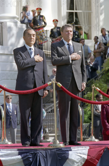U.S. President Ronald Reagan and Prime Minister Yasuhiro Nakasone  of Japan listening to national anthems on White House south lawn during state visit, Washington, D.C., USA, President Ronald Reagan White House Photographic Office, April 30, 1987