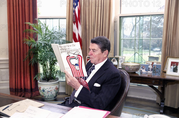 U.S. President Ronald Reagan reading a book "We can blow the whistle on Government waste" in the White House Oval Office, Washington, D.C., USA, President Ronald Reagan White House Photographic Office, December 19, 1984
