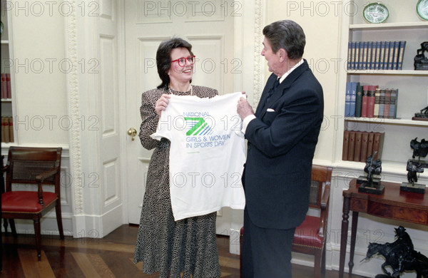 American tennis player Billie Jean King presenting U.S. President Ronald Reagan with a t-shirt in the White House Oval Office, Washington, D.C., USA, President Ronald Reagan White House Photographic Office, February 4, 1988