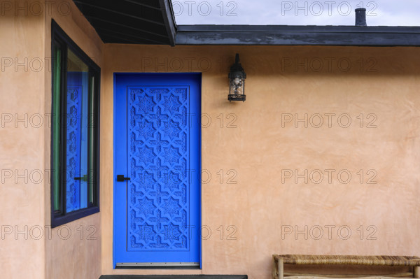 Blue carved wood door on stucco house