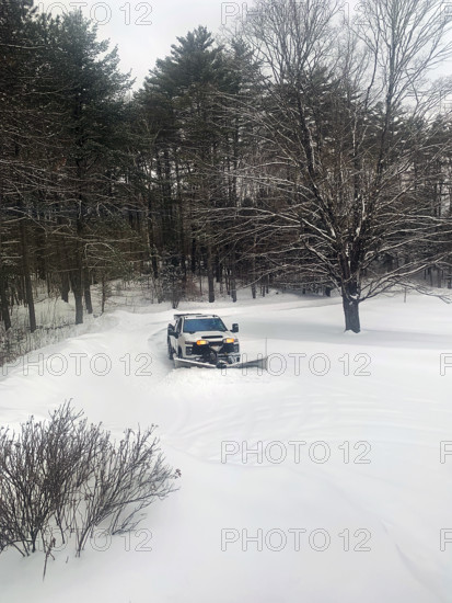 White pickup truck with plow attachment removing snow from residential driveway