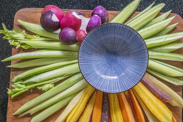 High angle view of fresh cut vegetables with blue bowl on wood board