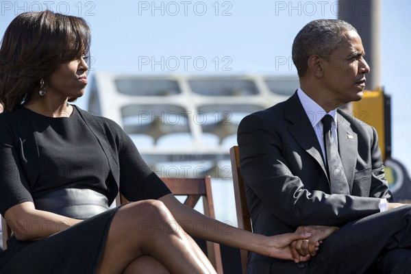 U.S. President Barack Obama and U.S. First Lady Michelle Obama holding hands as they listen to U.S. Representative John Lewis during an event to commemorate 50th Anniversary of Bloody Sunday and Selma to Montgomery civil rights marches, Edmund Pettus Bridge, Selma, Alabama, USA, Pete Souza, Office of White House Photography, March 7, 2015
