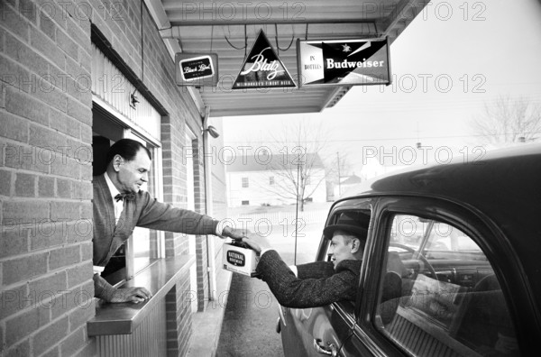 Store employee in drive-thru window handing six-pack of National Bohemian beer to customer in car, Marion S. Trikosko, U.S. News & World Report Magazine Photograph Collection, February 4, 1960