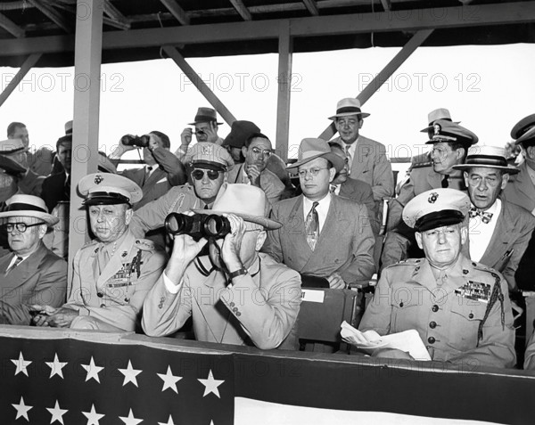 U.S. President Harry S. Truman peering through binoculars, with other dignitaries, watching weapons demonstration involving amphibious helicopter landings, United States Marine base at Quantico, Virginia, USA, Abbie Rowe, National Parks Service, Harry S. Truman Library, June 15, 1950