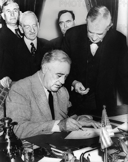 U.S. President Franklin D. Roosevelt signing declaration of war against Germany, marking U.S. entry into World War II in Europe, as U.S. Senator Tom Connally holds watch to fix exact time of declaration with (L-R): Senator Alben Barkley (KY), Senator Carter Glass (VA), Representative Joseph Martin (MA), White House, Washington, D.C., USA, U.S. Office of War Information, December 11, 1941