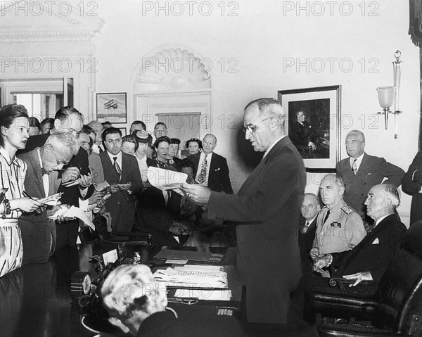 U.S. President Harry S. Truman announcing the surrender of Japan, ending World War II, to assembled reporters in the White House Oval Office. Seated behind President Truman are John Snyder, Admiral William D. Leahy, and U.S. Secretary of State James Byrnes, Washington, D.C., USA, Abbie Rowe, National Parks Service, Harry S. Truman Library, August 14, 1945
