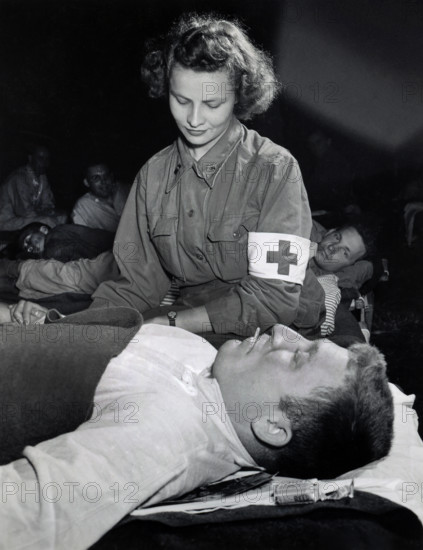 Lt. Elizabeth Babarsik, Canton, Ohio, checking temperature of Private John L. Bennett, Reading, Pennsylvania at field hospital, Normandy, France, U.S. Army Signal Corps, July 5, 1944