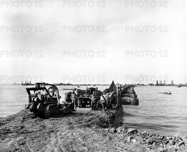 American soldiers expediting transportation of materiel at shore end of one of two projects, Mulberry and Gooseberry, vast landing platforms extending 1,000 yards into the channel from Omaha Beach, Normandy, France, U.S. Army Signal Corps, June 23, 1944