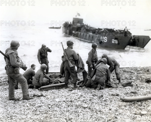 American soldiers applying artificial respiration on two other soldiers who reached the north coast of France in rubber life raft after their landing craft was sunk by enemy action while several hundred yards from shore, near Cherbourg, Normandy, France, Weintraub, U.S. Army Signal Corps, June 6, 1944