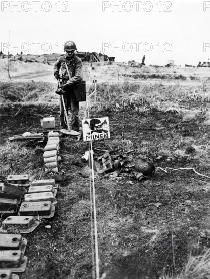1st Lieutenant Merle Kirstein, Des Moines, Iowa, going through German-marked minefield with detector to pick out any explosive mines that might be left, Normandy, France, U.S. Army Signal Corps, June 13, 1944