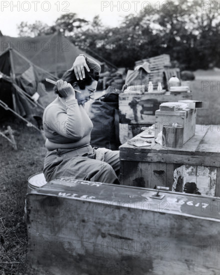 U.S. Lieutenant Frances Y. Slanger, U.S. Army nurse of Boston, Massachusetts, and one of the first nurses to arrive in the wake of the invading armies, taking time out from her arduous duties at a field hospital to fix her hair, Normandy, France, U.S. Army Signal Corps, June 15, 1944