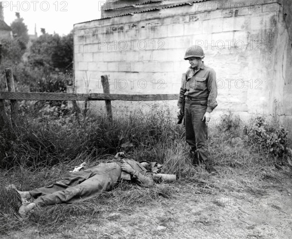 U.S. Sergeant Joseph C. Self of Harriman, Tennessee, looking over dead German sniper, Omaha Beachhead, near Vierville-sur-Mer, Normandy, France, Todd, U.S. Army Signal Corps, June 10, 1944