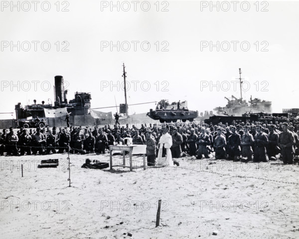 Chaplain (1st Lieutenant) Paul. J. McGovern, former pastor of St. Mary's Catholic church, Denvers, Massachusetts, conducting mass near one of the first American cemeteries to be constructed on Omaha Beach, Normandy, France, Weintraub, U.S. Army Signal Corps, June 25, 1944