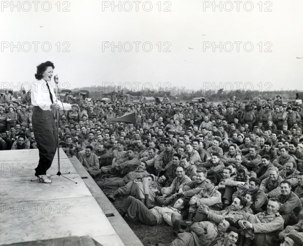 Crowd of GIs flock around an improvised platform to witness first U.S.O. camp show, France, U.S. Army Signal Corps, July 26, 1944