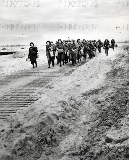 First arrivals of U.S. Women's Army Corps marching from disembarkation pier to transportation and trucks, Normandy, France, U.S. Army Signal Corps, July 15, 1944