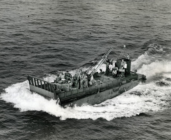Small landing boat transporting artillery and machinery back and forth between ships and beachhead, Normandy, France, U.S. Army Signal Corps, August 15, 1944