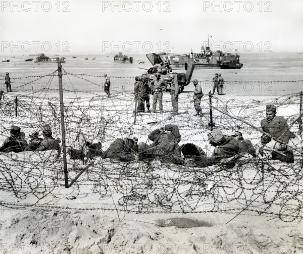 German prisoners resting in barb-wired enclosure after being interrogated by American soldiers, Utah Beach, La Madeleine, Normandy, France, Petrony, U.S. Army Signal Corps, June 6, 1944