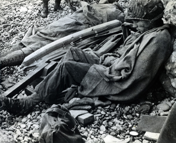 American soldier of 3rd Battalion, 16th Infantry Regiment, 1st Infantry Division, resting after storming ashore from landing craft, Omaha Beach, Colleville-Sur-Mer, Normandy, France, U.S. Army Signal Corps, June 6, 1944