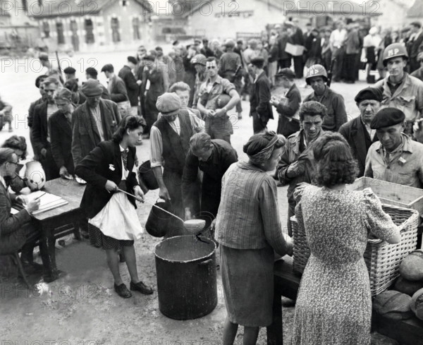 Homeless people who were being cared for by members of civil affairs unit queue up for noonday meal at displaced persons center where they were staying, Verdun, France, U.S. Army Signal Corps, September 16, 1944