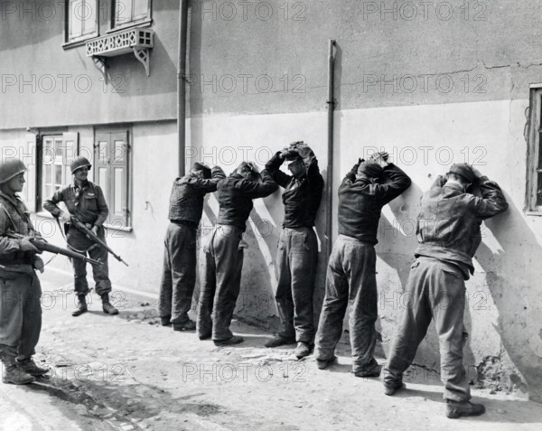 Pfc. Herbert Lusk and Sgt. Joseph F. Mannix guard SS troops captured by units of U.S. 1st Infantry Division, U.S. First Army, Dorsten, North Rhine-Westphalia, Germany, U.S. Army Signal Corps, April 11, 1945