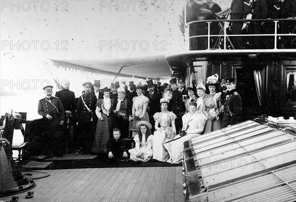 Sur le pont d'un yacht royal, autour du Roi Christian IX et de la Reine Louise de Danemark, les familles royales du Danemark, de Russie, de France, la Princesse Marie d'Orléans, et d'Angleterre