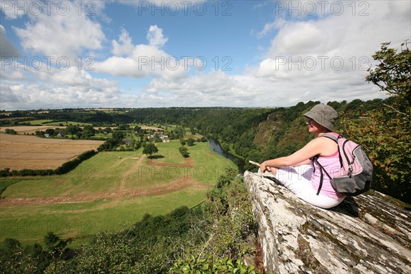 France, Normandie, Manche, pays de saint lo, conde sur vire, roches de Ham, randonneuse assise sur rocher contemplant le panorama, ciel nuageux, vallee,