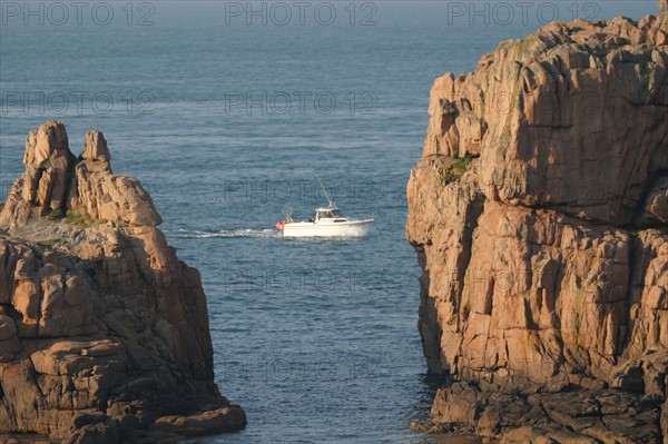 France, Bretagne, Cotes d'Armor, cote de granit rose, ploumanach, petit bateau passant entre deux rochers,