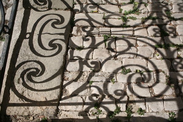 France, languedoc roussillon, gard, uzes, ombre de ferronneries d'un balcon sur le sol, paves, vieille ville, habitat traditionnel,