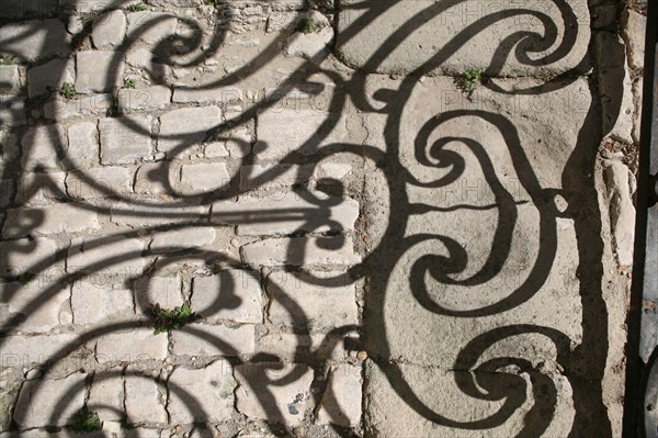 France, languedoc roussillon, gard, uzes, ombre de ferronneries d'un balcon sur le sol, paves, vieille ville, habitat traditionnel,