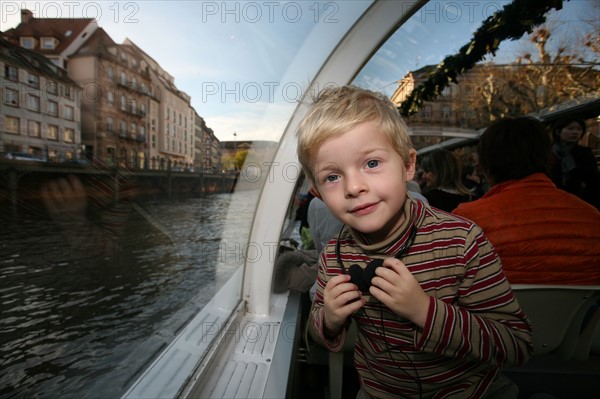 France, Alsace, Bas-Rhin, Strasbourg, croisiere fluviale sur l'Ill pendant la periode des marches de Noel, maisons sur les quais habitat traditionnel, la Petite France, audioguidage, enfant 4 ans, personnage autorise