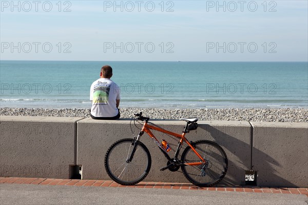 France, somme, entre picardie et Normandie, mers les bains, face au treport, pays de la bresle maritime, cote d'albatre, plage, galets, velo et jeune homme assis sur le parapet, station balneaire,