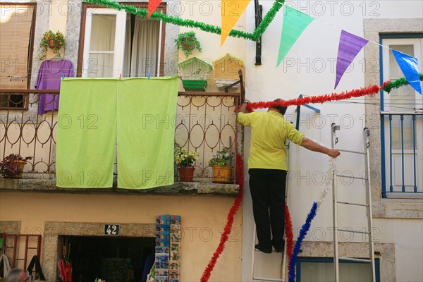 portugal, lisbonne, lisboa, signes de ville, alfama, quartier historique, detail habitat, preparation fete, guirlande, homme acrrochant decoration
Date : septembre 2011