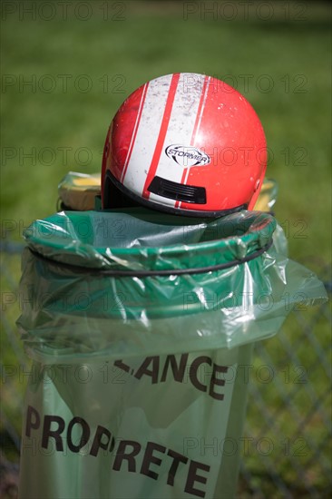 France, Région Ile de France, Paris 8e arrondissement, Parc Monceau, casque de moto rouge posé sur les poubelles vertes et jaunes