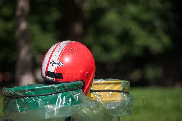 France, Région Ile de France, Paris 8e arrondissement, Parc Monceau, casque de moto rouge posé sur les poubelles vertes et jaunes