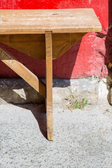 Banc en bois devant un mur rouge