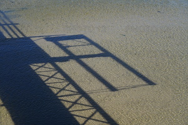 Shadow cast of a footbridge on the sand