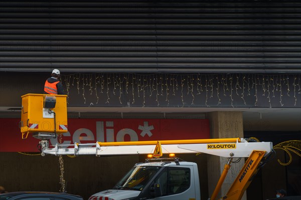 Paris, hanging Christmas decorations near the Montparnasse Tower