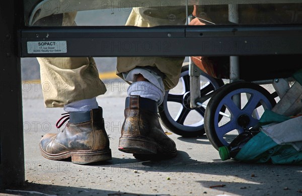 Paris, shoes of a man sitting in a bus shelter