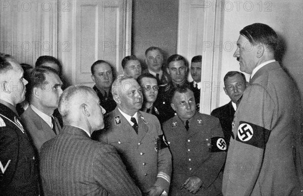 Adolf Hitler. Der Führer im Kreise seiner nächsten Mitarbeiter am Abend der Reichstagswahl vom 29. März 1936. Le Führer entouré de ses proches collaborateurs au soir de l'élection au Reichtag, le 19 mars 1936.
