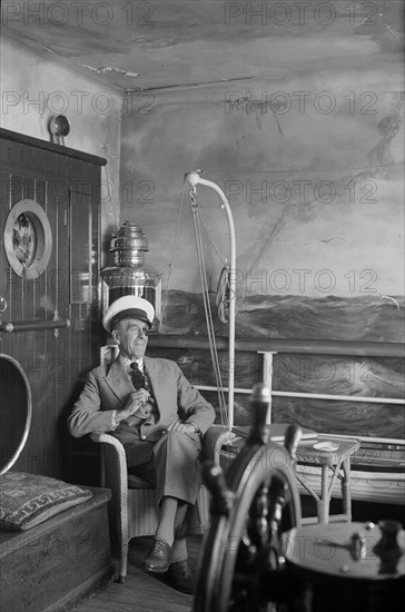 A man in a sailor's cap and eyepatch sits in a reconstructed ship's cabin, c1945-c1965