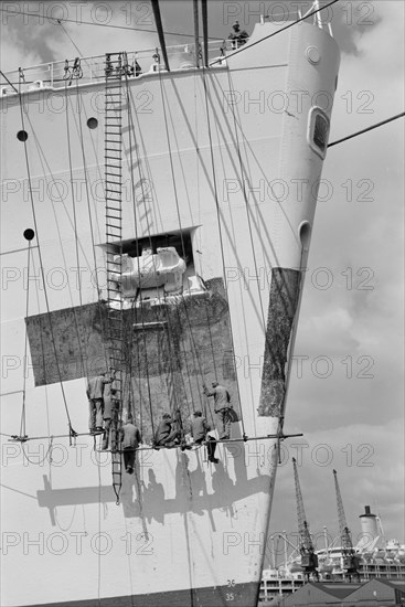 Workmen repairing the bow of a ship in London docks, c1945-c1965