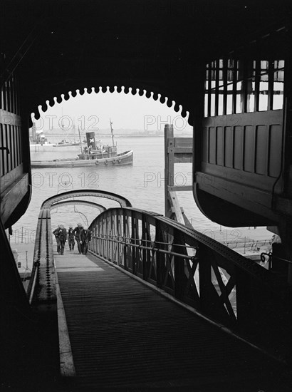 Men walking up a wooden bridge on a river, c1945-c1965