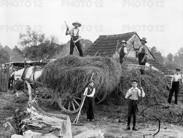 Men and boys with tools and a haycart, c1860-c1922